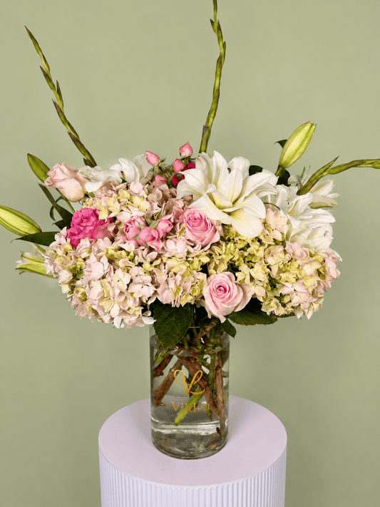Dolce Bloom is a a soft and graceful floral arrangement featuring creamy hydrangeas, blush roses, and white lilies.