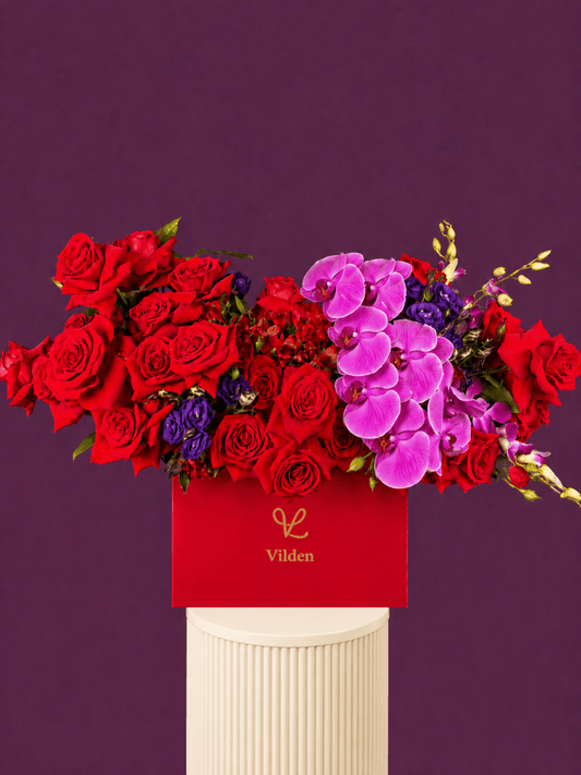 Ruby Orchid is a luxury red rose and pink orchid floral arrangement in a red Vilden box on a blush ribbed pedestal.