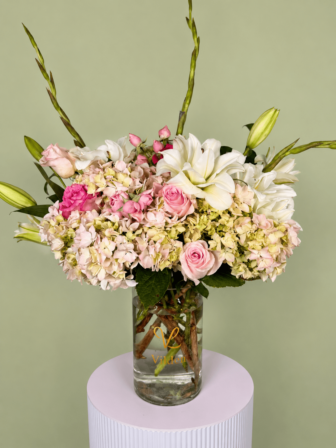Dolce Bloom is a  a soft and graceful floral arrangement featuring creamy hydrangeas, blush roses, and white lilies.