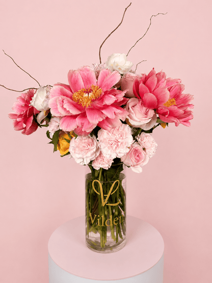Peony Muse Vase Arrangement with pink peonies, soft roses, carnations, and delicate floral accents in a clear Vilden vase.