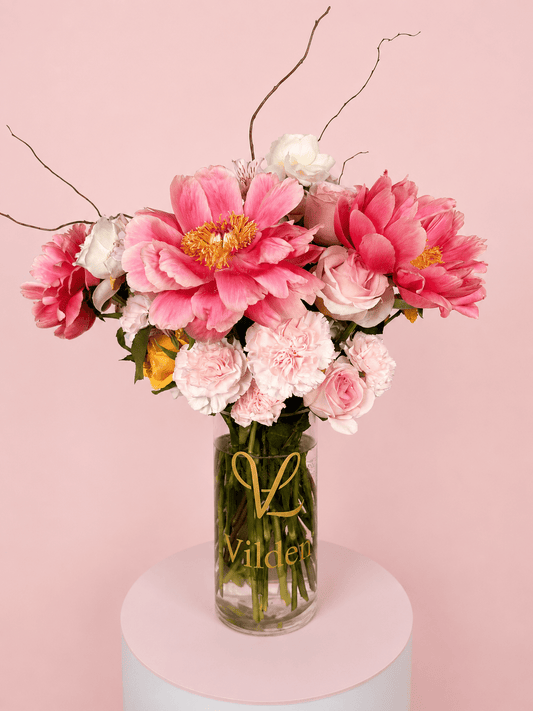 Peony Muse Vase Arrangement with pink peonies, soft roses, carnations, and delicate floral accents in a clear Vilden vase.