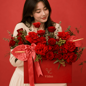 Rosso Forte red floral arrangement in a Vilden box with a model in a cream outfit