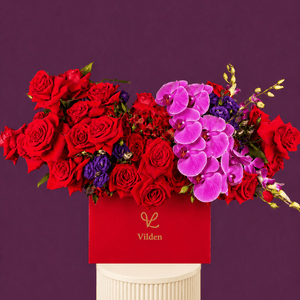 Ruby Orchid is a luxury red rose and pink orchid floral arrangement in a red Vilden box on a blush ribbed pedestal.