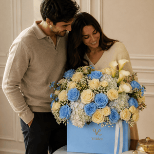 Serenade in Blue flower box with blue and cream roses, calla lilies, and a couple in an elegant room.