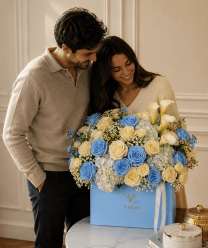 Serenade in Blue flower box with blue and cream roses, calla lilies, and a couple in an elegant room.