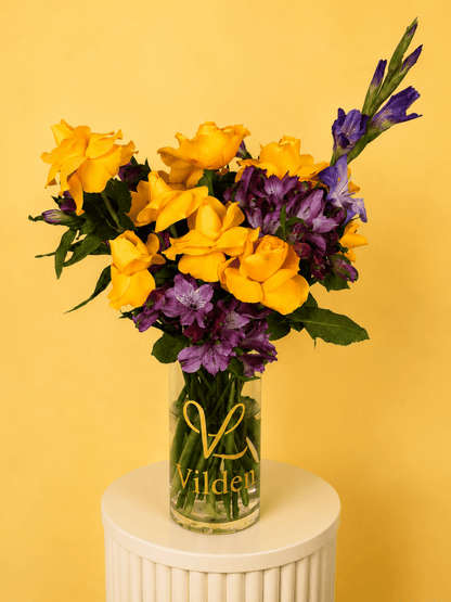Sunlit Royale, a golden and violet flower arrangement bouquet featuring yellow roses, purple gladiolus arranged in a vase