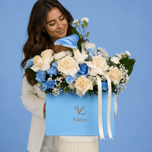 Tranquil Blue flower box with cream roses, blue blooms, and female model on blue studio background.