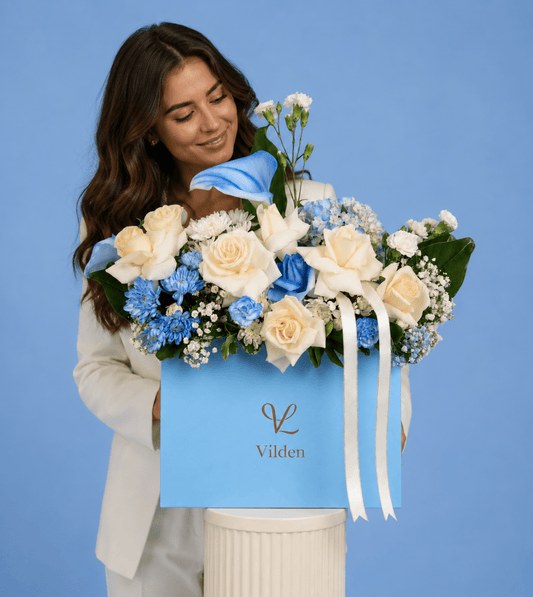 Tranquil Blue flower box with cream roses, blue blooms, and female model on blue studio background.