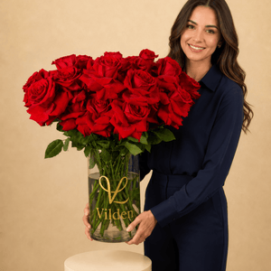 Vilden Rouge arrangement in a clear Vilden vase with a model holding it. 