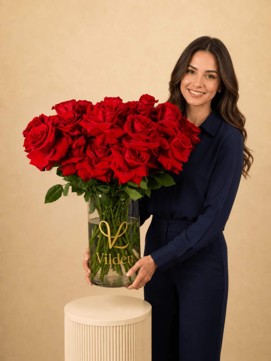 Vilden Rouge arrangement in a clear Vilden vase with a model holding it. 