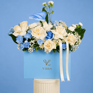 Tranquil Blue arrangement exudes serenity and calm with soft cream roses, delicate blue blooms, and a graceful calla lily.