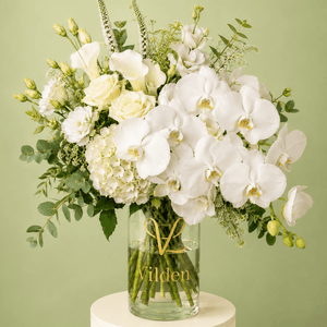 Luxury White Opera arrangement with cream roses, white calla lilies, hydrangea, and fresh greenery in a clear Vilden vase.