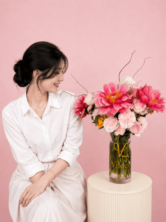 Peony muse arrangement with soft pink carnation and soft blooms next to a girl model in the Vilden studio.
